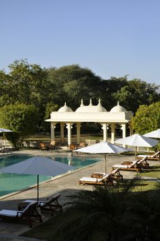 Sunbeds by a swimming pool around architecture reflecting the ancient heritage of Udaipur, India