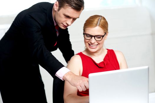 Business team in action. Man pointing at laptop while woman looks into it