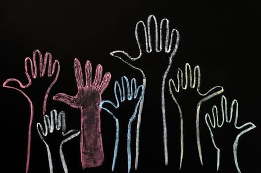 Happy volunteering hands on a blackboard background in colorful chalk