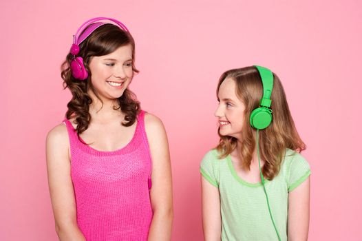 Two teenage friends enjoying music together and looking at the other