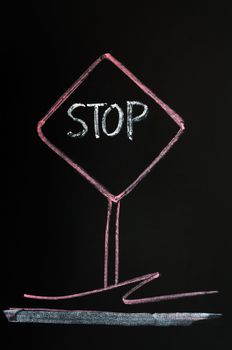 Stop warning sign drawn with red chalk on a blackboard background