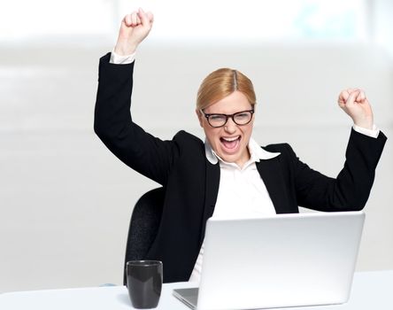 Caucasian corporate woman enjoying success with both hands raised up