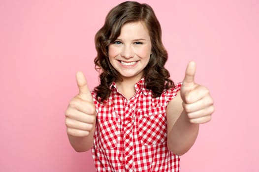 Gorgeous girl showing double thumbs up against pink background