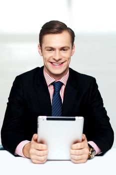 Cheerful male executive holding touch screen enabled digital device