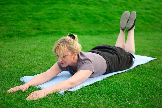 middle aged woman keeping fit with exercises in a park