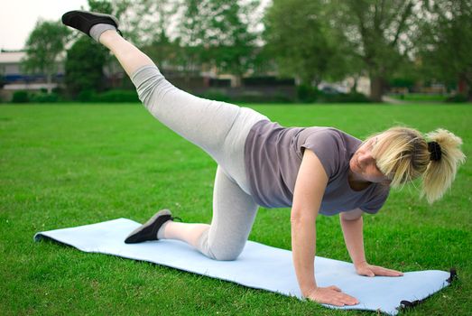 middle aged woman keeping fit with exercises in a park