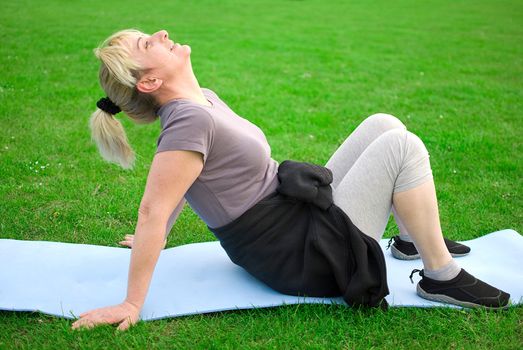 middle aged woman keeping fit with exercises in a park