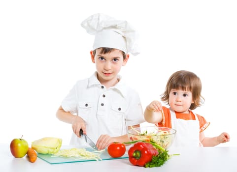 Two smiling kids mixing salad, isolated on white