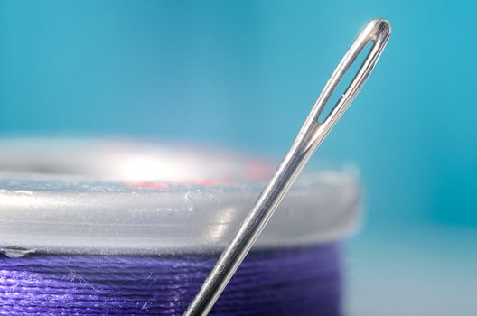 Macro view of a spool of thread and a needle.