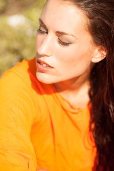 Portrait of young beautiful model posing on outdoors with orange shirt