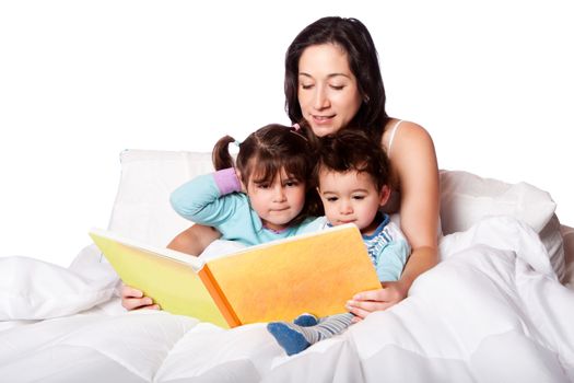 Mother reading bed time story book to daughter and son kids in bed, isolated.