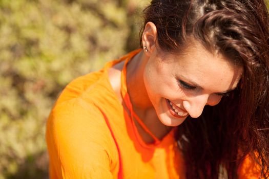 Portrait of young beautiful woman laughing wearing orange shirt