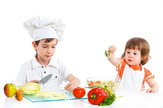 Two smiling kids mixing salad, isolated on white