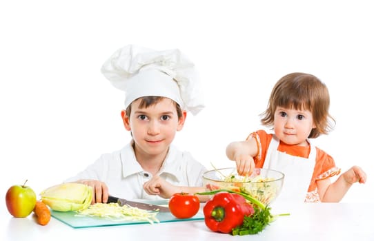 Two smiling kids mixing salad, isolated on white