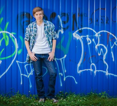 Young smile teenager in front of blue graffiti