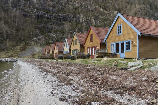 many small colored holiday homes at coastline in norway