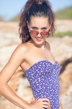 Sexy vintage model in swimsuit posing on the beach with glasses