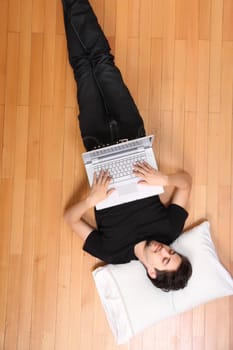 A young hispanic man surfing with a Laptop on the floor.