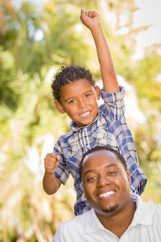 Happy Mixed Race Father and Son Cheering with Fist in the Air at the Park.
