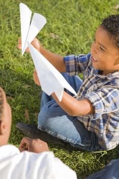 Happy Mixed Race Father and Son Playing with Paper Airplanes in the Park.
