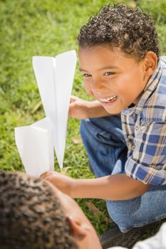 Happy Mixed Race Father and Son Playing with Paper Airplanes in the Park.
