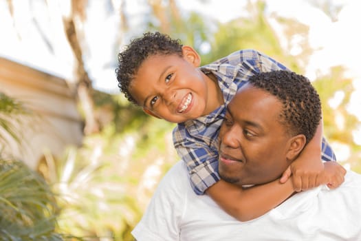 Happy Mixed Race Father and Son Playing Piggyback in the Park.