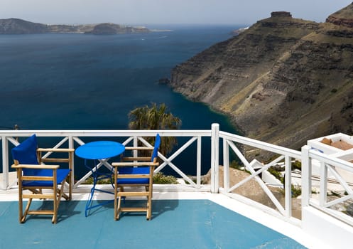 Caldera view in Santorini island with blue chairs and the table 