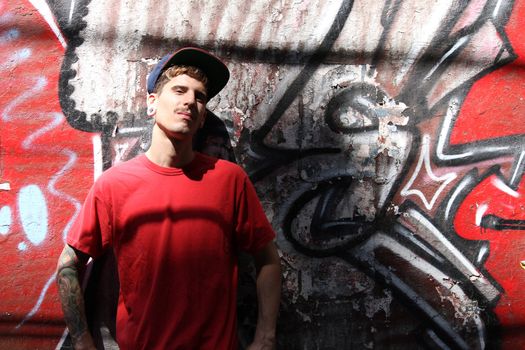 A young Rapper leaning against a wall.