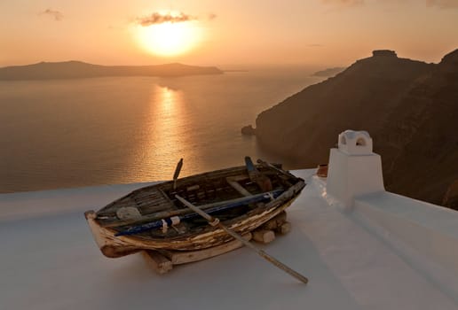 Sunset in Santorini island with the boat as a decoration of the house roof