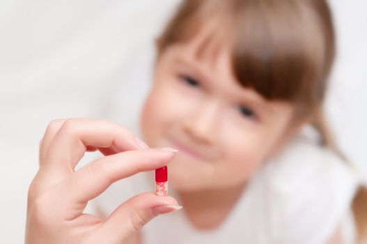 Woman give red pill to little girl