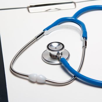 Stethoscope and pen on empty paper sheet