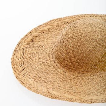 An unadorned woven straw sunhat or sombrero with a wide brim isolated on white.