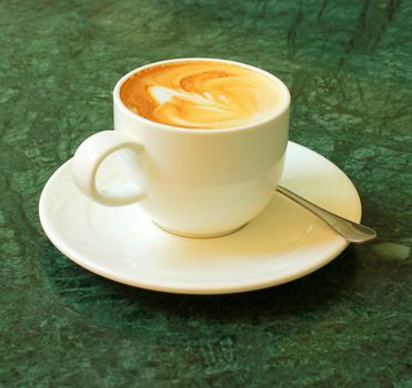 Cappuccino or latte coffee on table with flower chair