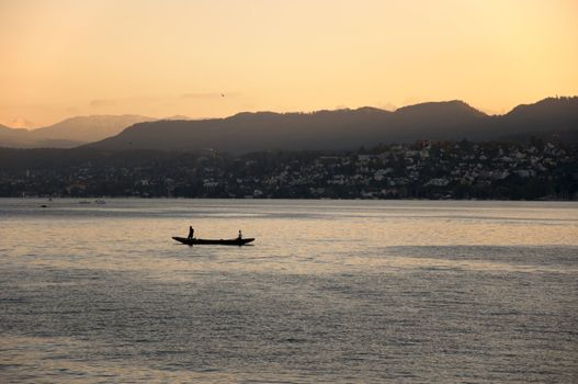 Boat in lake during sunset. Mountains in the background.