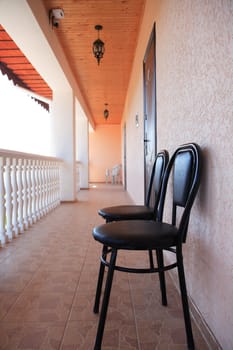 Pair of chairs standing on long terrace with white railing
