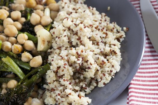 Steaming plate of broccoli and chickpeas served with bulgar and quinoa mix.