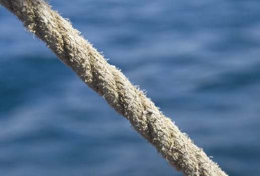 Stretched tight thick rope against blue sea water