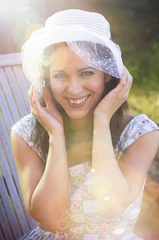 Happy woman in the summer season with hat in a park, with sunburst