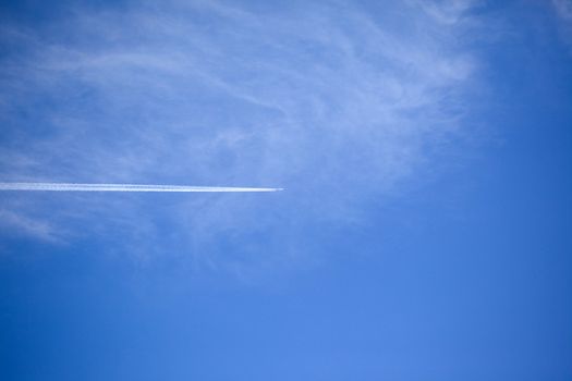 Plane with vapor stripes against the blue sky