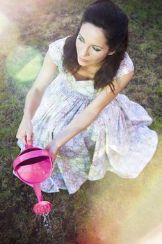 romantic young woman in spring watering with shower pink