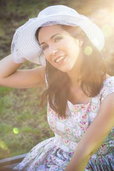 Happy woman in the park with hat under sunburst
