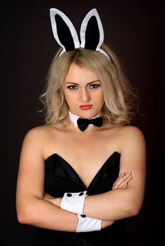 A sullen girl in sexy bunny costume against a dark background