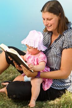 beautiful little girl reading book with her mother