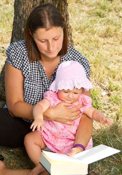 beautiful little girl reading book with her mother