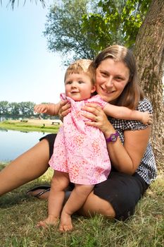 Mother holding daughter outdoors smiling 