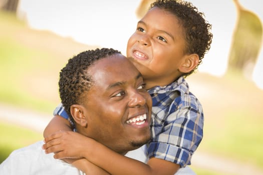 Happy African American Father and Mixed Race Son Playing Piggyback in the Park.