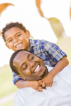 Happy African American Father and Mixed Race Son Playing Piggyback in the Park.