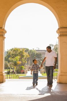 Happy African American Father and Mixed Race Son Holding Hands Walking in the Park.