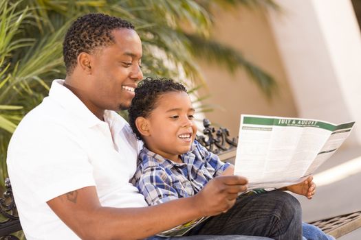 Happy African American Father and Mixed Race Son Having Fun Reading Park Brochure Outside.