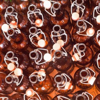 Background texture pattern of empty brown beer bottles with integral attached porcelain swing-top caps in a brewery bottling plant filling line